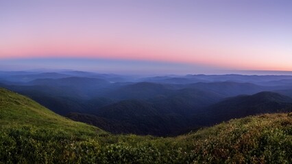 Fototapeta premium Vibrant twilight hues cast over rolling hills in an expansive mountain landscape at dusk