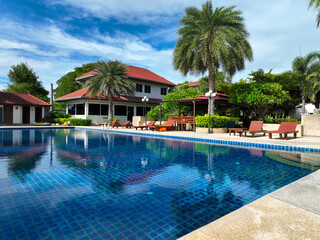 Inviting tropical resort swimming pool with crystal clear water reflecting blue sky surrounded by...