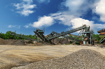 Crushing machinery, cone type rock crusher, conveying crushed granite gravel stone in a quarry open pit mining. Minning industry gravel quarry conveyor.