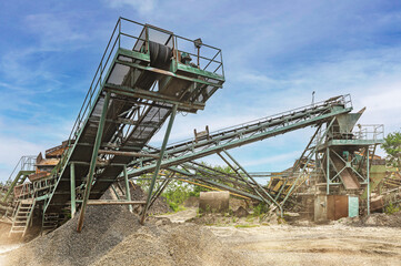 Crushing machinery, cone type rock crusher, conveying crushed granite gravel stone in a quarry open...