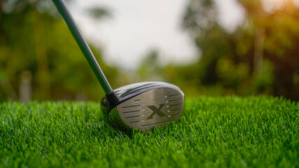 Golf clubs on a green lawn in a beautiful golf course with morning sunshine.