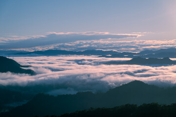 A serene spring dawn at Lion Head Mountain, Taiwan. Orange skies meet flowing white clouds, with silhouettes of power line towers.