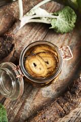 Preparation of homemade herbal tincture from fresh sliced burdock root and alcohol in a glass jar