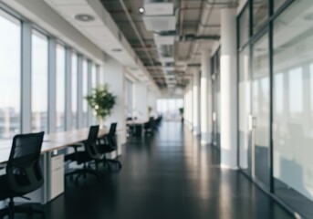 A blurred view of an office space with desks chairs and large windows letting in natural light inside