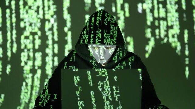 Anonimowy haker w masce z kodem Matrix projektowanym na twarzy z laptopem 
