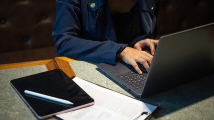 Businesswoman working area with laptop, tablet and documents on small desk, in warm atmosphere and space for text.