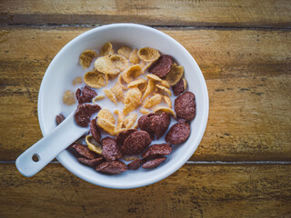 Bowl of cereal with milk on wooden table, breakfast concept.