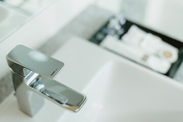 Modern chrome faucet on a white sink in a bathroom. Cleanliness