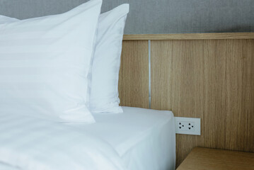 Hotel bed with white linens and pillows, room interior.