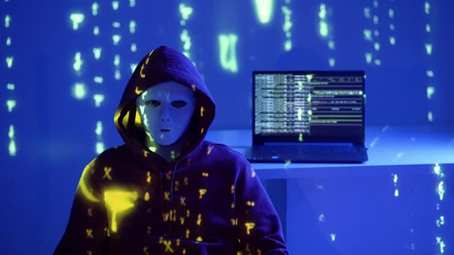 Haker w masce siedzi przy laptopie w ciemnym pokoju z migającym czerwono-niebieskim światłem syreny policyjnej i kodem matrix, cyberprzestępczość w akcji nocą
