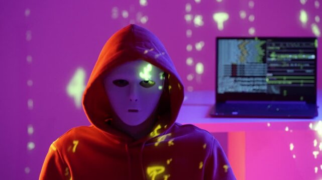 Anonimowy haker w masce siedzi w ciemnym pokoju z laptopem, kod matrix i migające policyjne światła niebiesko-czerwone tworzą cybernetyczną atmosferę zagrożenia i przestępstwa