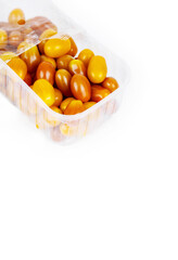 Plastic container of fresh yellow and orange cherry tomatoes isolated on white background. Tomatoes in transparent pack, perfect for grocery, retail, and food market visual content. Copy space