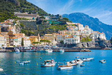 Picturesque view of Amalfi, Italy, with colorful houses, excursion boats, blue waters of Mediterranean Sea in sunny summer day. Amalfi coast is most popular travel and holiday destination in Europe
