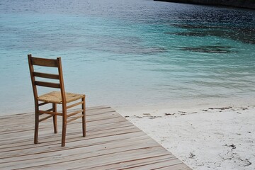 Fototapeta premium Serene Beach Chair on Wooden Dock, Tranquil Ocean View