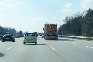 Busy highway scene with trucks and cars transporting logs in broad daylight setting