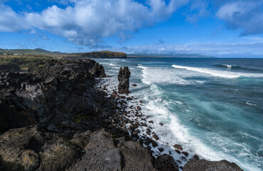 Panorama der Lava-Felsenküste von Ribeira Seca, Ribeira Grande, Nordküste von São Miguel. Schwarze Lavaformationen (Ignea nigra), blauer Himmel und Meer in Komplementärfarben. Blick erhöht Richtung Sa