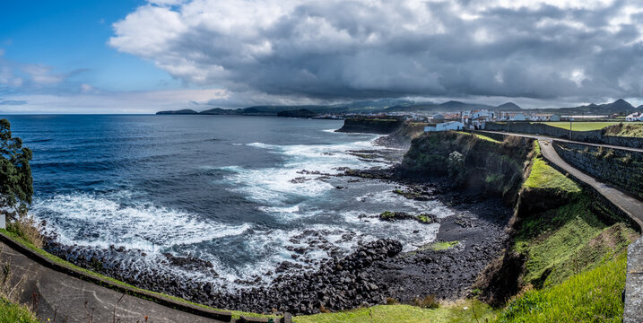 Dramatische Bucht von Cahetas an der Nordk&uuml;ste von S&atilde;o Miguel. Im Vordergrund gr&uuml;ne Landschaft (Viriditas naturae), dahinter Rabo de Peixe. Wechselhaftes Azorenwetter mit Sonne und Wolken.