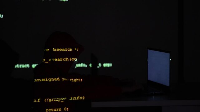 Anonimowa postać przy laptopie z pulsującym światłem i projekcją cyfrowego kodu