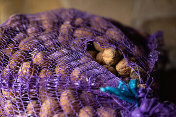 Full bag (grocery net) of walnuts, harvest storage.