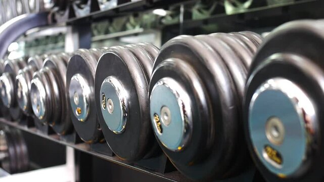 The moving focus stops on one of many dumbbells of different weights close-up