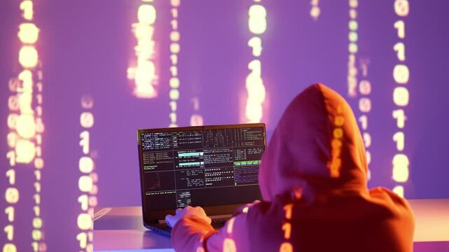 Osoba w kapturze pracująca przy laptopie z terminalem systemowym i kodem &ndash; analiza danych, haker, cyberbezpieczeństwo, kodowanie, systemy