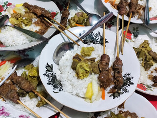 Satay and curry with pickles on a stacked plate, satay gulai is a traditional Indonesian food.