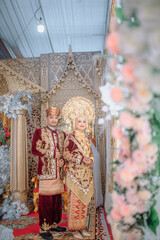 Obraz premium A wedding portrait of a Muslim couple wearing traditional Minangkabau attire from West Sumatra, featuring the iconic gold suntiang headdress.