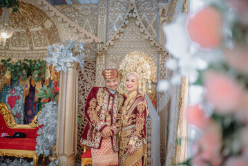 Bride and groom in traditional Minangkabau wedding dress, featuring rich fabrics, gold accessories, and cultural elegance from West Sumatra