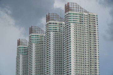 Fototapeta premium Baywalk Apartment Building Shot From Muara Angke Port Featuring Unique Architectural Design Against Clouds