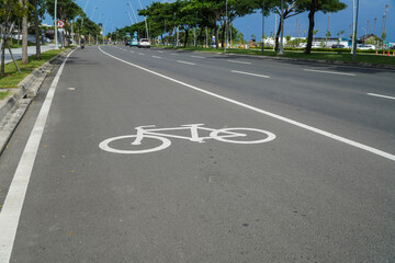 Obraz premium Bicycle Lane Marking on Asphalt Road in Urban Environment with Greenery and Blue Sky