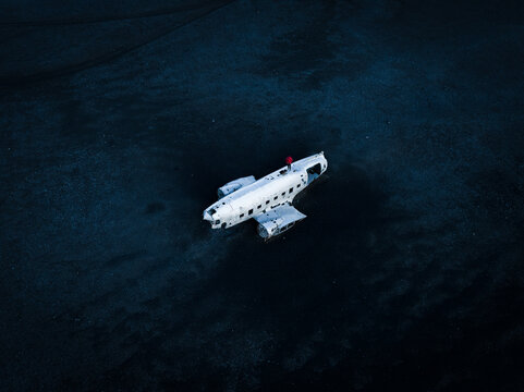 On Iceland&rsquo;s stark black sands, a stranded DC-9 wreck stands out. The figure perched atop its fuselage adds a sense of scale, so seamlessly blending human curiosity with nature's rugged, moody allure.