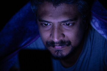 Mobile phone addiction, man using mobile phone at night sparing his sleep, social media addiction