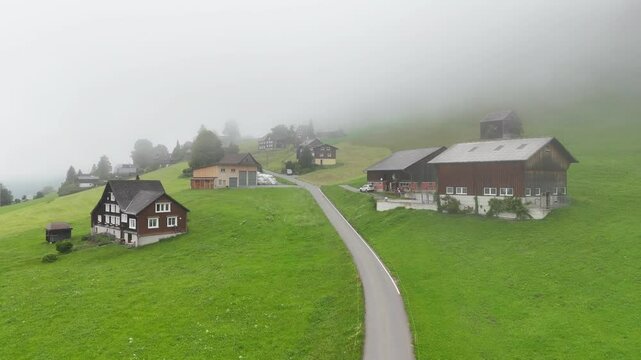 7 juli 2025, Wildhaus-Alt Sint Johann, Switzerland. Drone flight above the some houses and farms in alpine green meadow,  charming village near the Alpstein mountain range. Small alpine town.