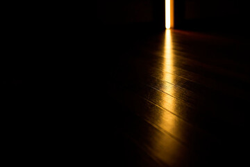 Light through a half-open door in a dark room. Space for text.