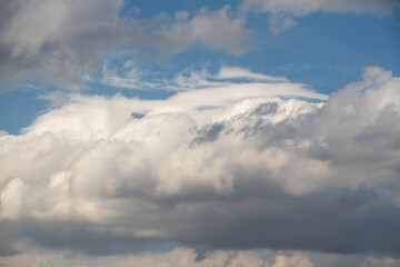 Blue sky with fluffy white close up clouds.