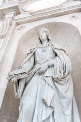 Fototapeta premium A woman in a white dress statue stands in front of a building