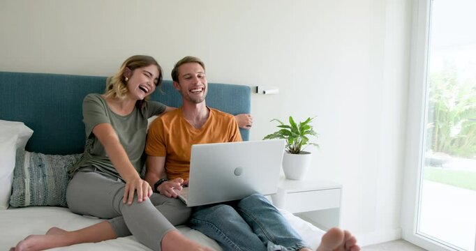 Video chatting, Couple relaxing on bed with laptop, enjoying quality time at home