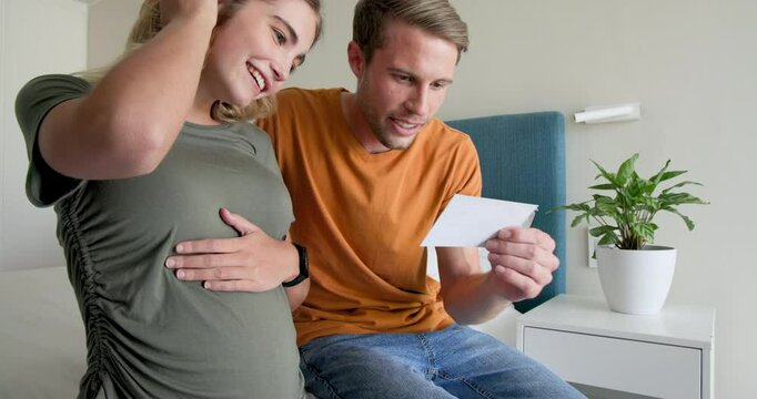 Expectant couple joyfully bonding at home, touching pregnant belly with love