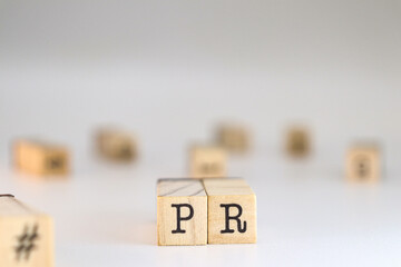 Public relations acronym. PR letters written on wooden cubes isolated on white background with copy space. Concept of concept of corporate prestige, communication strategies