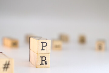 Public relations acronym. PR letters written on wooden cubes isolated on white background with copy space. Concept of concept of corporate prestige, communication strategies