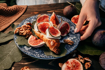 Woman puts plate with camembert cheese croissants, figs. Brie, healthy juicy