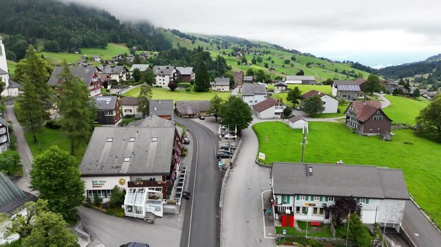 7 juli 2025, Wildhaus-Alt Sint Johann, Switzerland. Drone flightbackwards above the village centre of Wildhaus, a charming village near the Alpstein mountain range. Small alpine town centre, houses. S