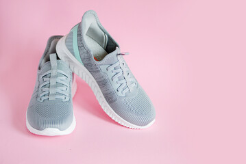 Gray women's sneakers close-up on a pink background