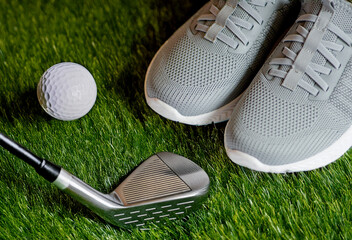 Close-up of woman's legs in sneakers and golf club near ball on grass