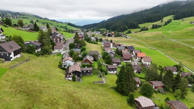 7 juli 2025, Wildhaus-Alt Sint Johann, Switzerland. Drone flightbackwards above the village centre of Wildhaus, a charming village near the Alpstein mountain range. Small alpine town centre, houses. S