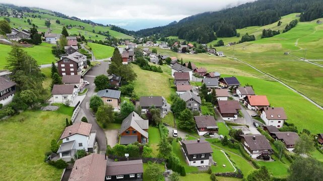 7 juli 2025, Wildhaus-Alt Sint Johann, Switzerland. Drone flightbackwards above the village centre of Wildhaus, a charming village near the Alpstein mountain range. Small alpine town centre, houses. S