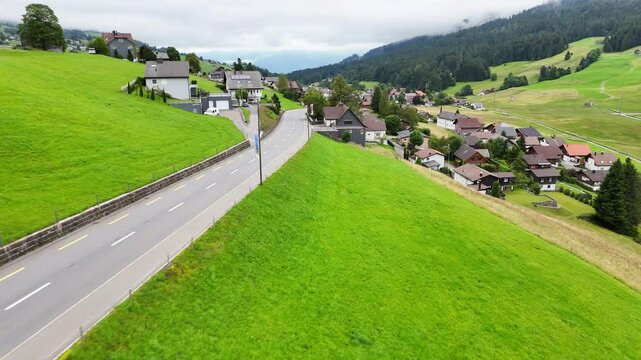 7 juli 2025, Wildhaus-Alt Sint Johann, Switzerland. Drone flight backwards above the village centre of Wildhaus, a charming village near the Alpstein mountain range. Small alpine town centre, houses. 