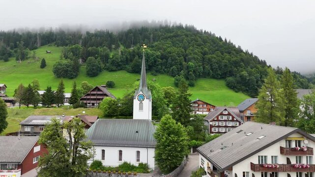 7 juli 2025, Wildhaus-Alt Sint Johann, Switzerland. Drone flight above the village centre of Wildhaus, a charming village near the Alpstein mountain range. Small alpine town centre, houses. Surrounded