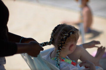 holding braids with pink color on little kid head. stylist applying braiding hair on young baby.