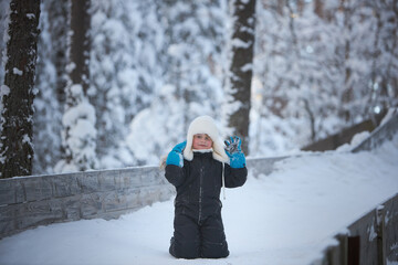 A young child, bundled up against the cold, stands on a snow-covered bridge, amidst the enchantment of a winter landscape.